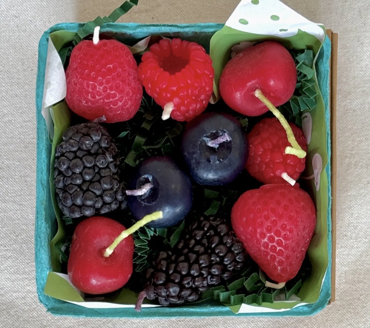 Strawberry, raspberry, blackberry and blueberry shaped beeswax candles in a paper berry basket