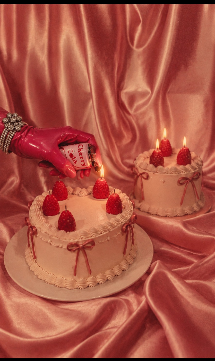 Strawberry beeswax candles burning on frosted cakes