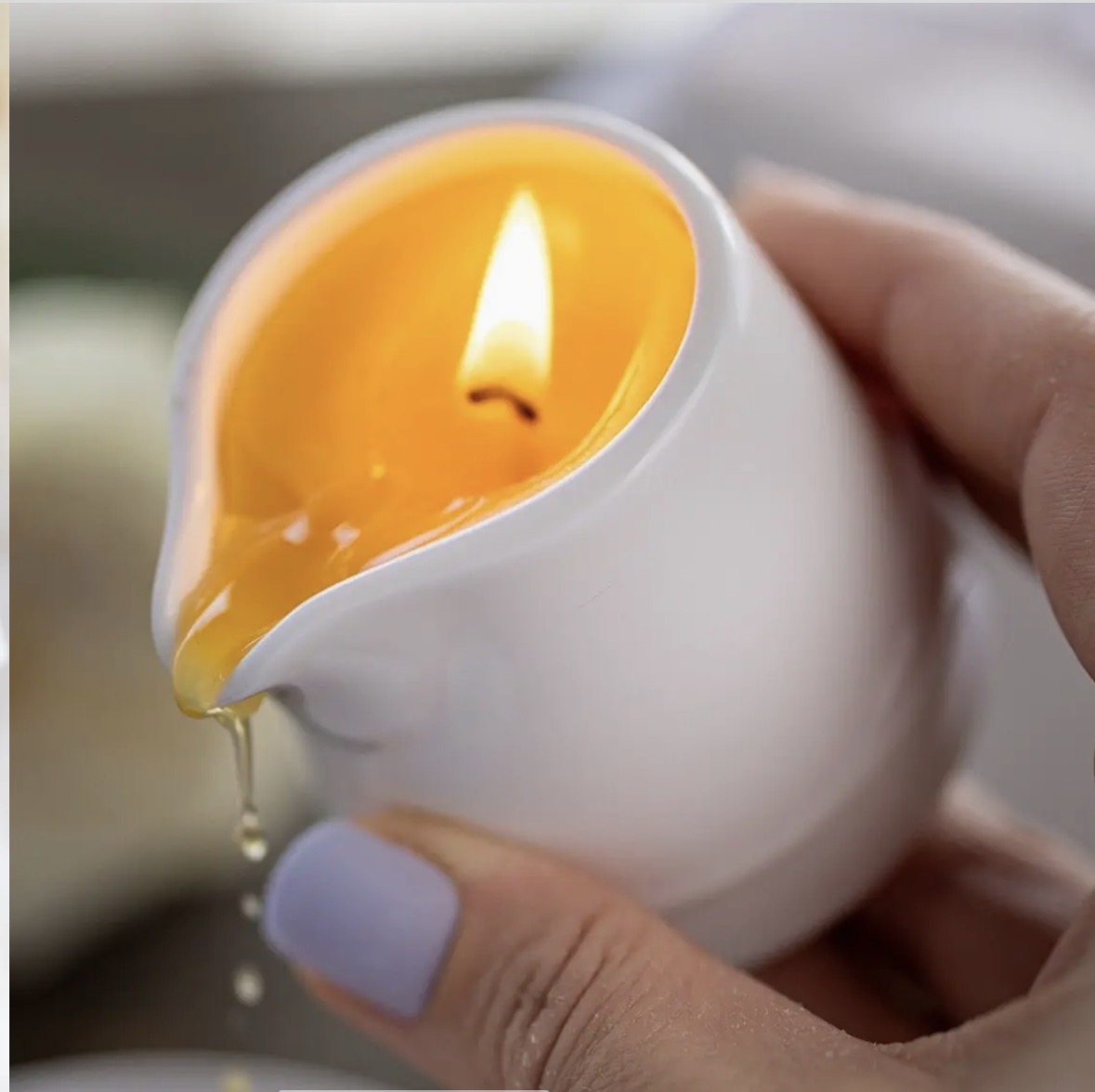 A ceramic massage candle being poured as warm oil into a hand