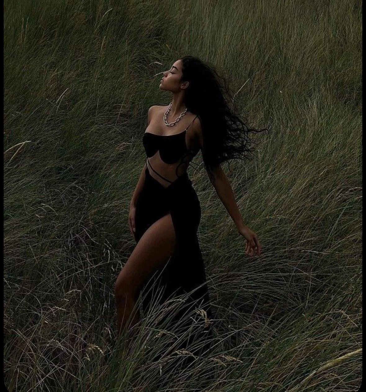 Woman standing tall in tall green grass, embodying calm confidence and authorship of her reality