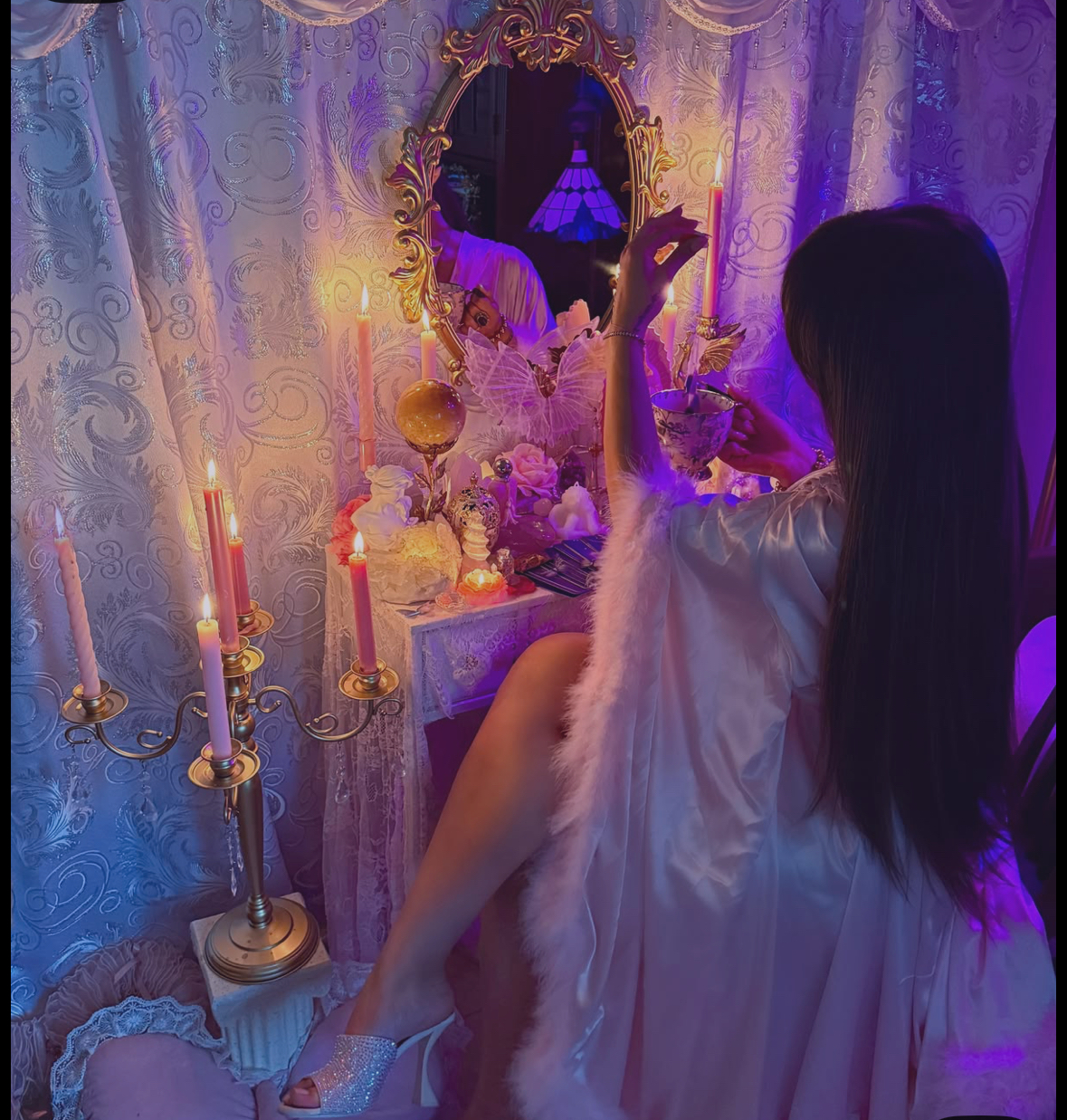 Soft candlelit vanity with mirrors and violet light, a scene of quiet renewal