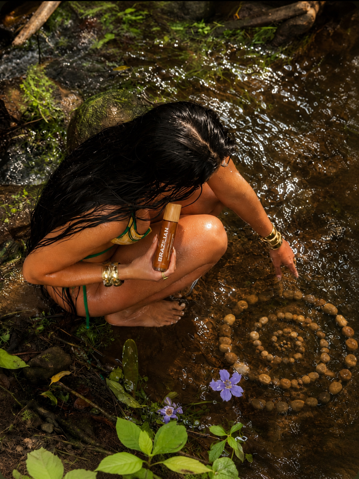 Glowing bronze skin holding Kristi Spiral body oil